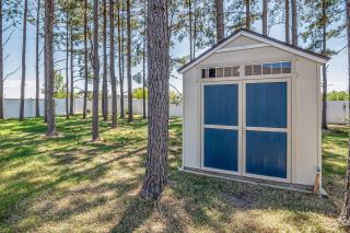 Abri de jardin blanc à double porte installé sous des pins
