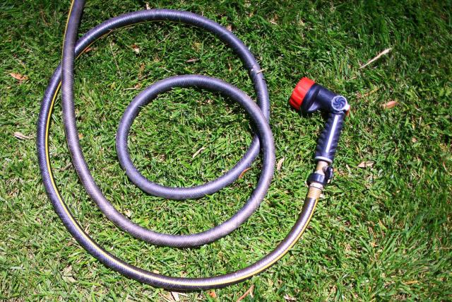 Diamètre, longueur, couches : le tuyau adapté à chaque terrain Tuyau d'arrosage enroulé sur le gazon, avec son pistolet multijet